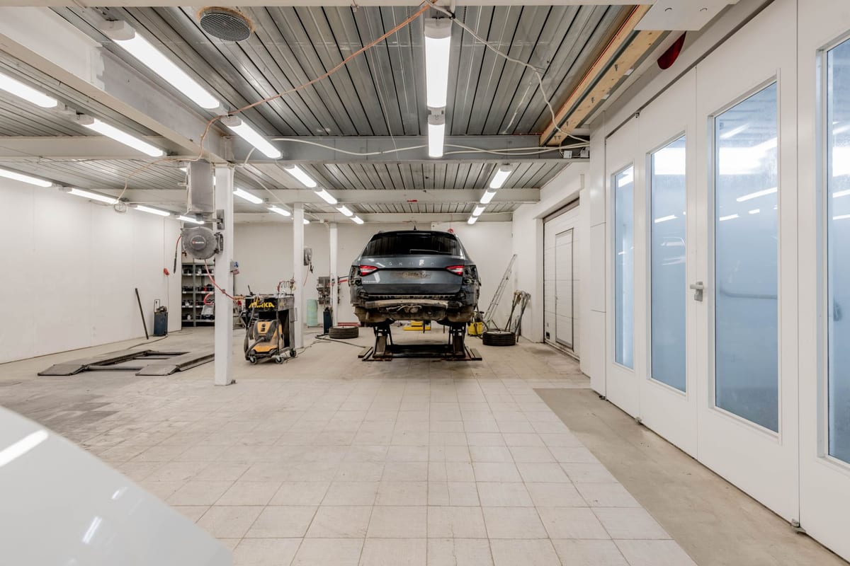 Well-lit garage with a car on a hydraulic lift ready for repair.